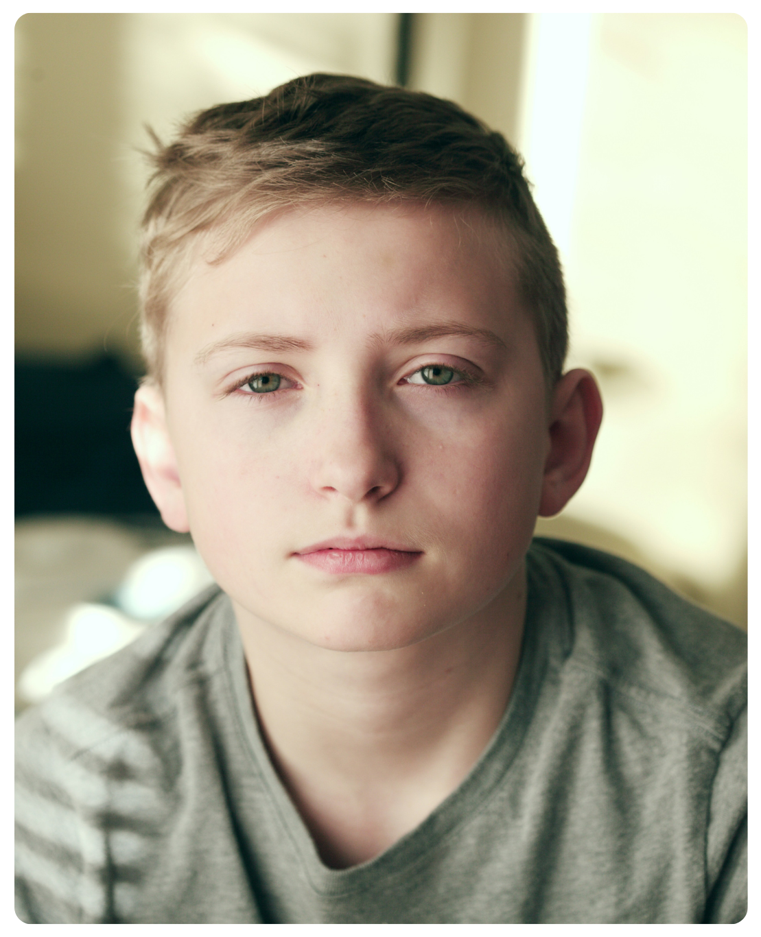 A 10-13 year old caucasian boy looking at the camera with a serious face. 