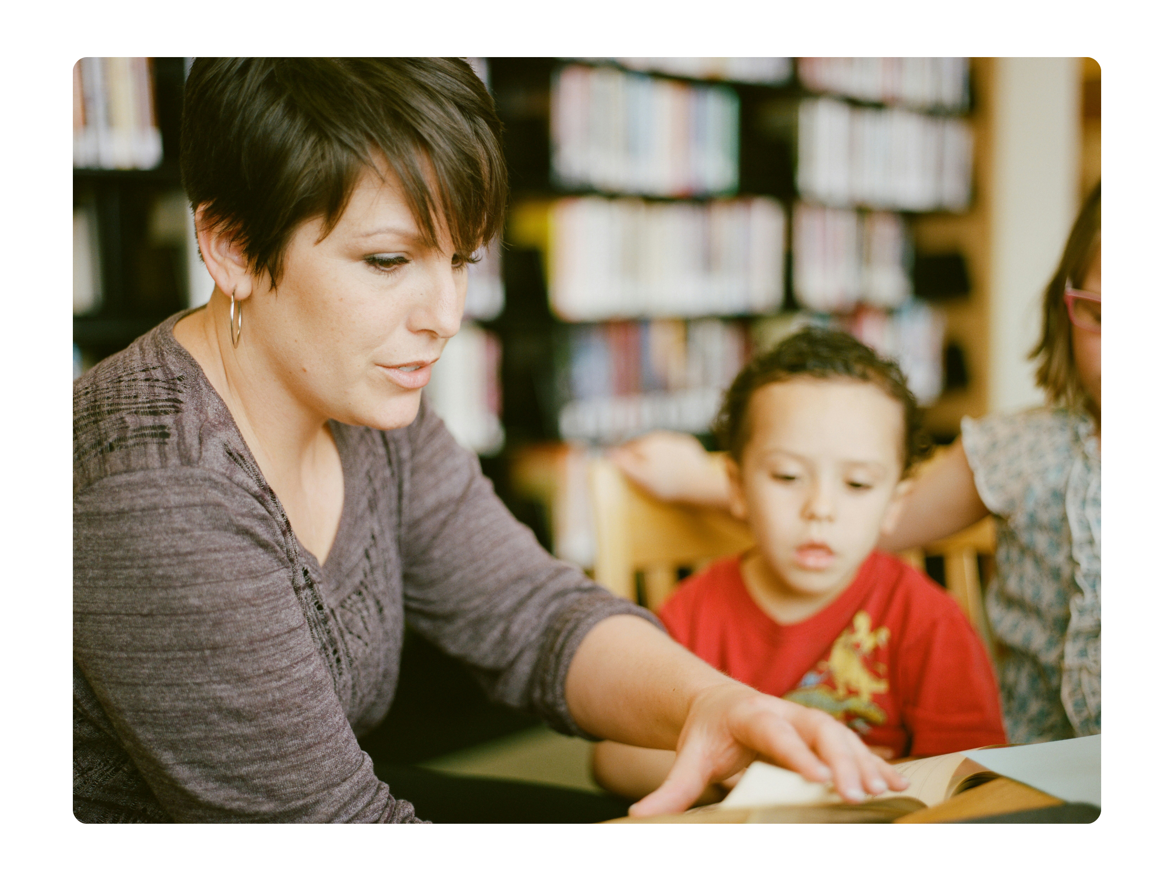 Teacher working with a young student in a classroom or library